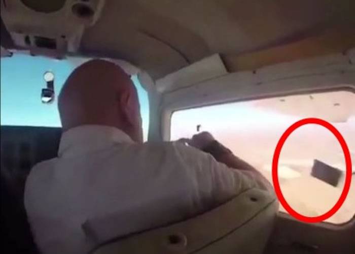 外国男子飞机上开窗照相 相机遭气流卷走